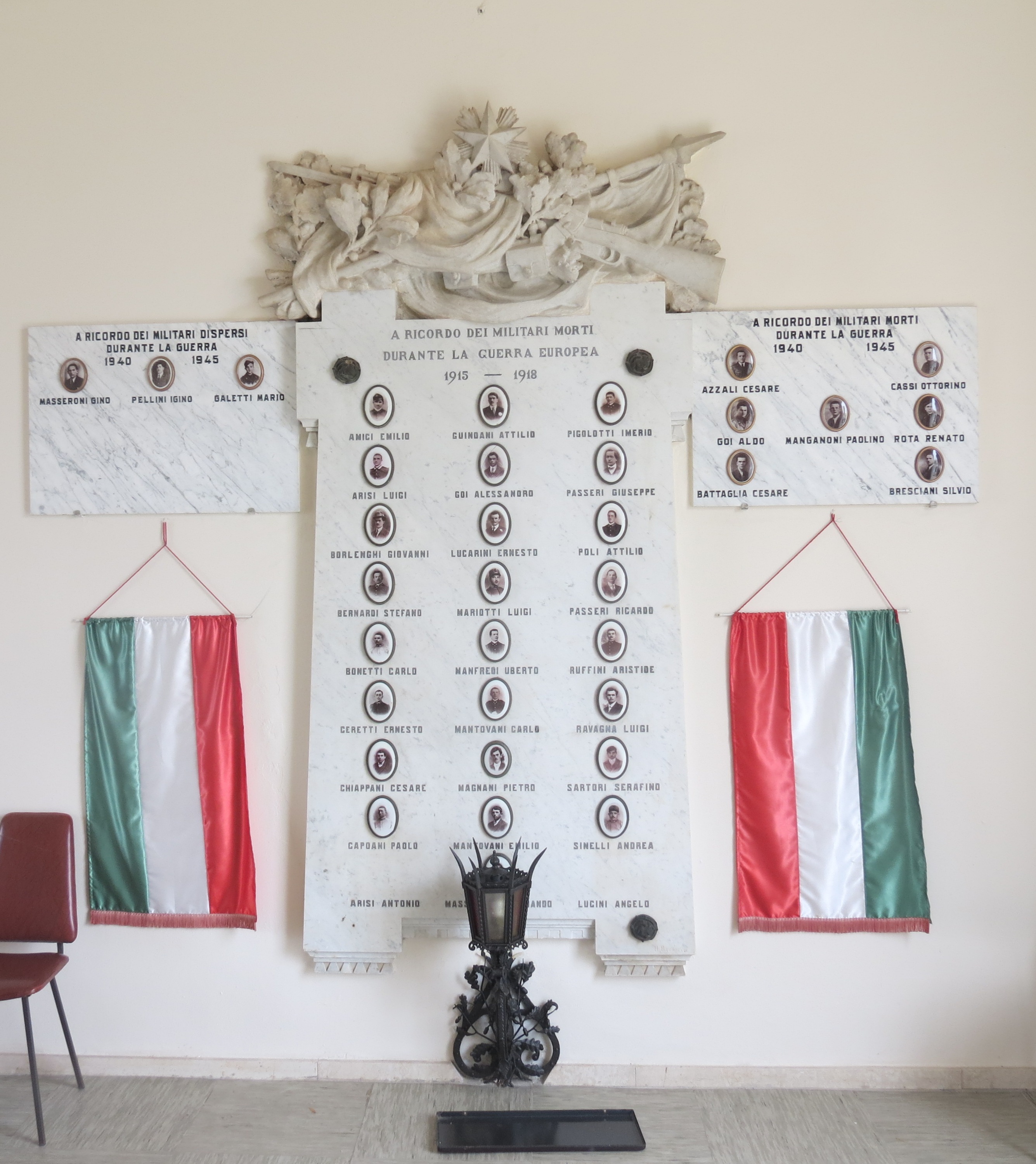 Bandiera avvolta attorno ad armi e rami di quercia e alloro (in alto) (lapide commemorativa ai caduti) di Bagarelli U (sec. XX)