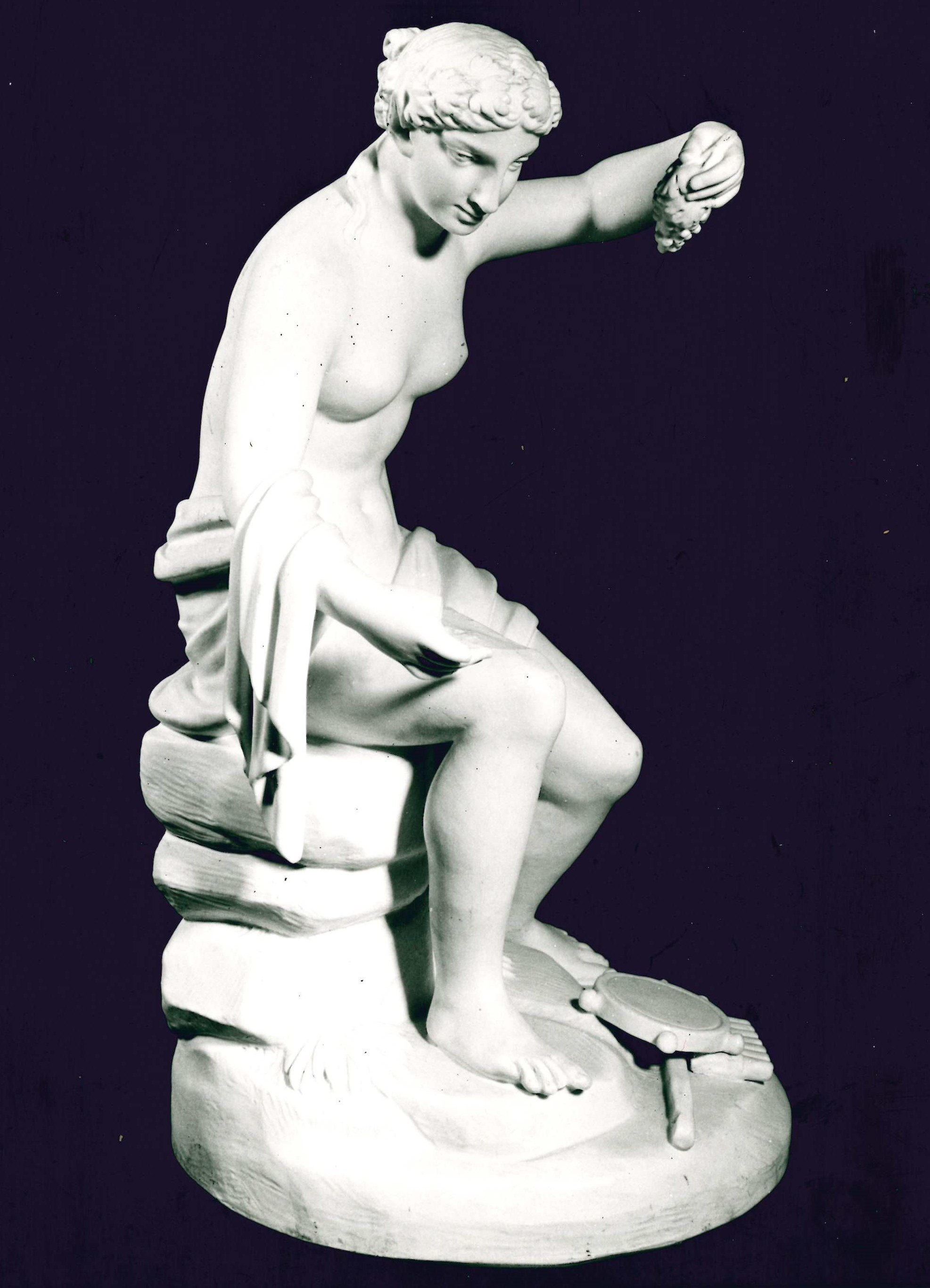Baccante, figura femminile seduta con tamburello e siringa a terra e grappolo di uva in mano (statuetta) - ambito viennese (sec. XIX)