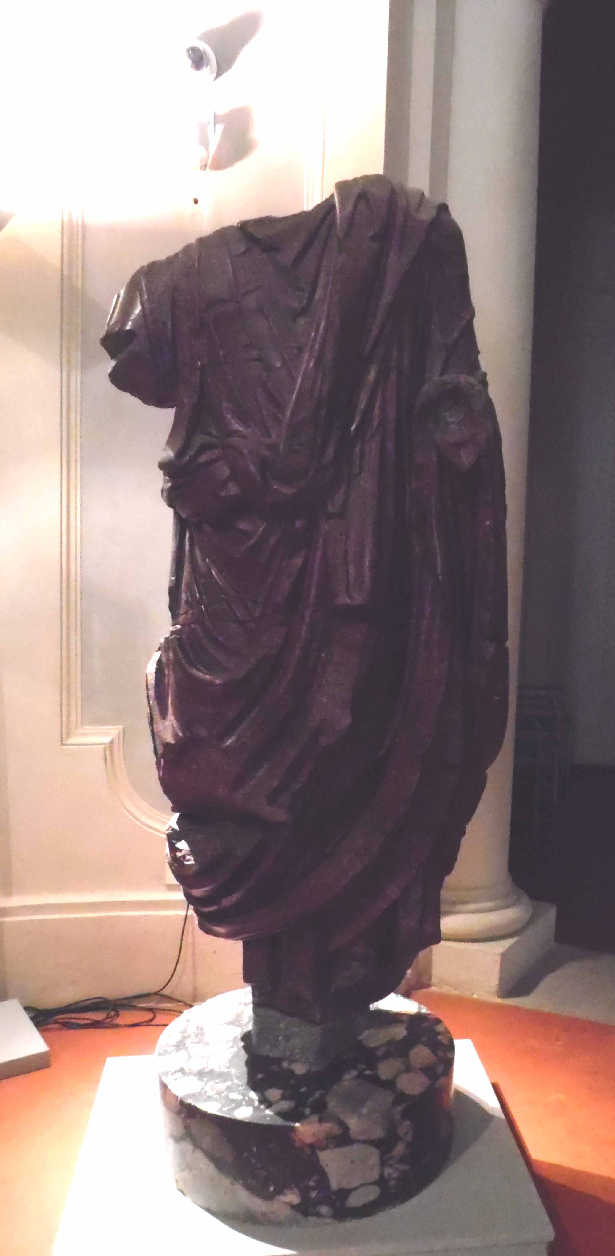 Statua acefala di uomo con toga in porfido egiziano (statua) - ambito romano (Eta' di Adriano)