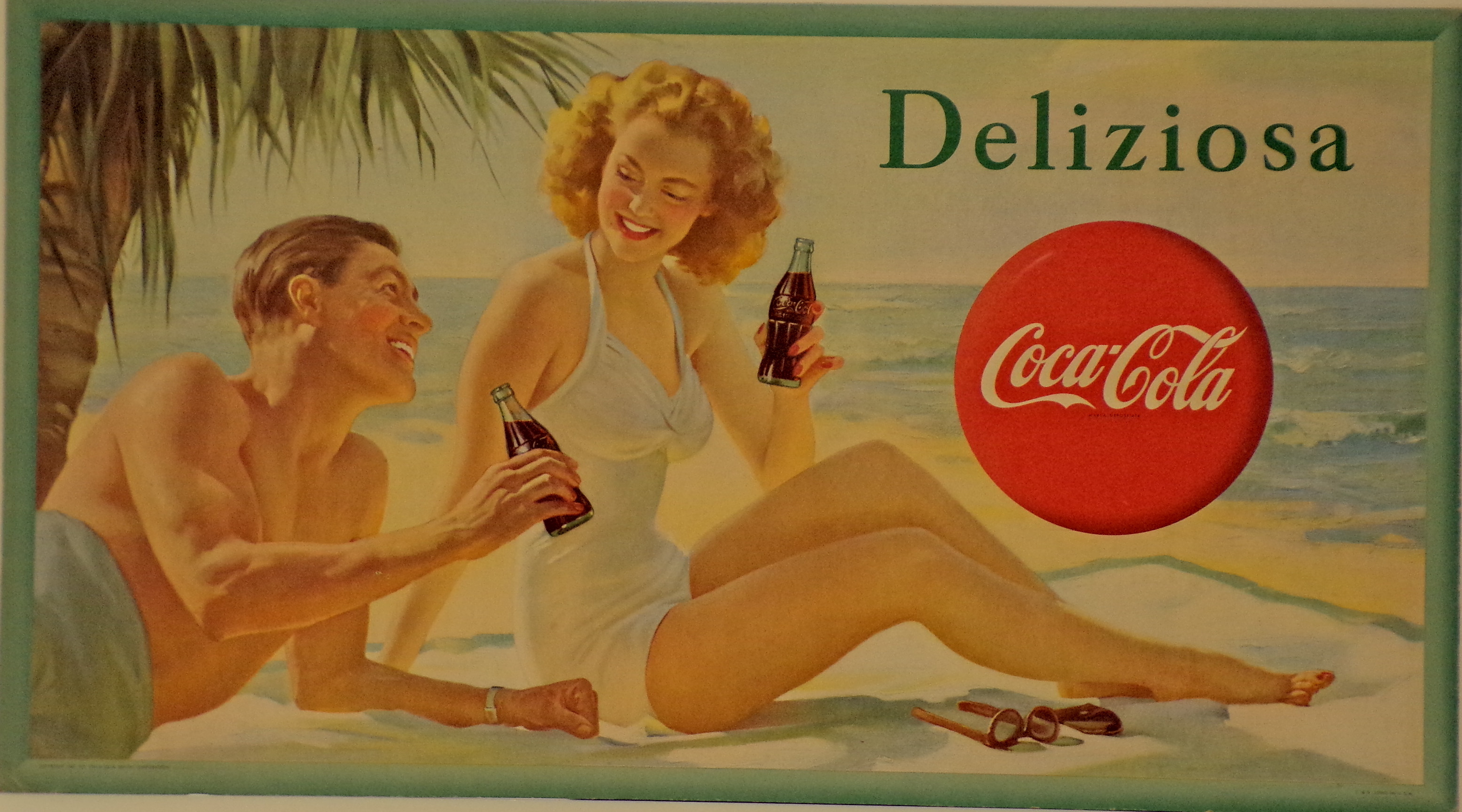 Coca-Cola. Deliziosa, Giovane coppia su una spiaggia assolata beve Coca-Cola all'ombra di una palma (Cartello - da vetrina, opera isolata) di S. & B. Litho, U.S.A - ambito milanese (metà XX)